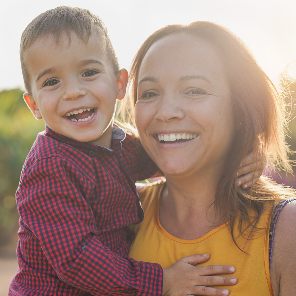 A smiling mother holding her son, reflecting the strength and support of families served by MaaPaa